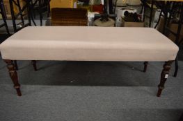 A large upholstered stool on turned legs.