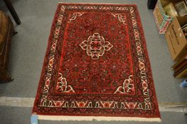 A Persian style rug, red ground with geometric decoration, 163cm x 114cm.