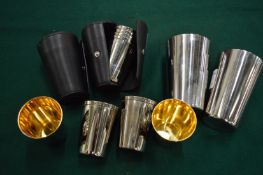 Two leather cased sets of spirit cups and a pair of stainless steel cups.