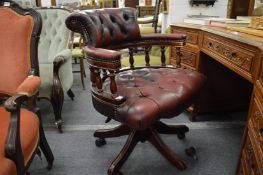 A burgundy leather upholstered swivel office chair.