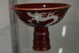 A sang de boeuf stem cup decorated with a dragon.