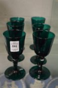 A set of six dark green glass wine glasses.