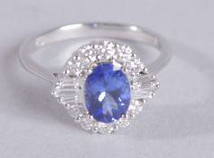 A CERTIFIED 18CT WHITE GOLD OVAL-CUT TANZNAITE AND RBC AND TAPERED BAGUETTE DIAMOND HALO RING.