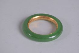 A GOLD LINED, APPLE GREEN JADE BANGLE.