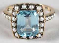 A 9CT GOLD, BLUE TOPAZ AND SEED PEARL RING.