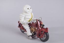 A CAST IRON MICHELIN MAN ON A MOTORBIKE. 8.5ins long.