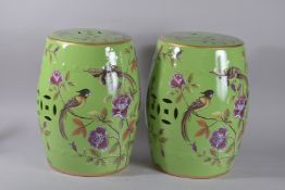 A PAIR OF CHINESE GREEN PORCELAIN BARREL SEATS painted with birds and flowers. 17ins high.