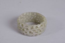 A PIERCED CELADON JADE BANGEL 2.75ins diameter.