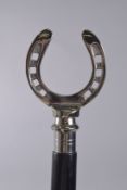 A WALKING STICK WITH HORSESHOE HANDLE.