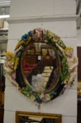 A DECORATIVE CONTINENTAL MAIOLICA OVAL WALL MIRROR, the pottery frame mounted with putti and