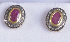 A PAIR OF OVAL RUBY AND R/C DIAMOND HALO STUDS, set in gold plated silver, boxed. Rubies, 0.45ct
