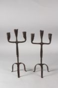 A PAIR OF METAL FORGED CANDLE HOLDERS on tripod bases. 11ins high.