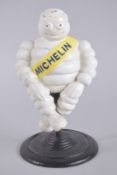 A PAINTED CAST IRON MICHELIN MAN on a circular base. 11ins high.