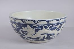 A CHINESE BLUE AND WHITE PORCELAIN CARVED DRAGON BOWL. 27cms diameter,
