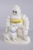A PAINTED CAST IRON MICHELIN MAN WITH A DOG. 8ins high.