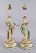 A PAIR OF PAINTED SPELTER LAMPS, boy and girl, on circular bases, after BRUCHON. 22ins high.