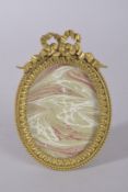 A GOOD ORMOLU OVAL FRAME WITH RIBBON AND BOW CRESTING. 6ins x 4.25ins.