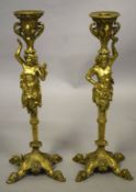A GOOD PAIR OF BRASS CANDLESTICKS with classical figures, on four curving legs. 11ins high.