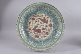 A LARGE CHINESE TURQUOISE AND UNDERGLAZE RED CARVED PORCELAIN CHARGER, with central panel of phoenix