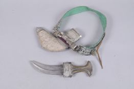 AN OMANI WHITE METAL MOUNTED JAMBIYA, with bovine horn handle, 30.5cm long.