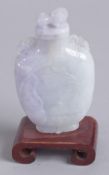 A 20TH CENTURY CHINESE CARVED JADEITE SNUFF BOTTLE, mounted to a wooden stand, 8cm high.