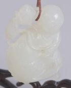 A 19TH CENTURY CHINESE CARVED WHITE JADE PENDANT; figure holding a carp, on a hanging wooden
