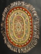 AN INDIAN EMBROIDERED OVAL TEXTILE WITH VARIOUS INSET STONES.