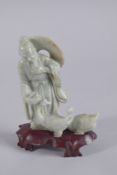 A CHINESE CARVED JADEITE FIGURE ON HARDWOOD STAND, figure 13.5cm high.
