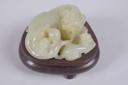 A CHINESE CARVED JADE LION GROUP ON HARDWOOD STAND, jade 9cm wide.