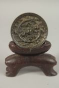 A CHINESE CIRCULAR BRONZE MIRROR, with carved soapstone stand, mirror 9cm diameter.