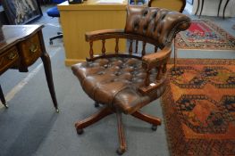 A brown leather upholstered office swivel armchair.