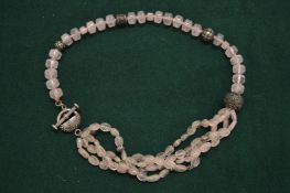 A silver and rose quartz necklace.