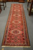 A Persian runner, red ground with stylised decoration, 290cm x 74cm.