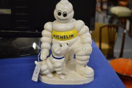 A cast iron Michelin man patting a dog.