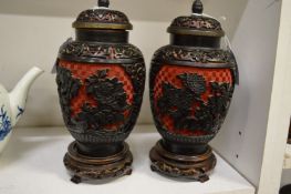 A pair of cinnabar lacquer jars and covers on later wooden stands.