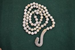 A jade bead necklace with curving serpent pendant.