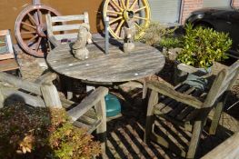 Wooden circular patio table with three armchairs and a parasol stand.