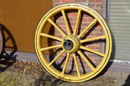 A large pair of yellow painted wagon wheels.