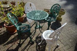 A small green painted aluminium patio table with two pairs of similar chairs, a pair painted