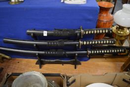 A set of three Japanese swords on a stand.