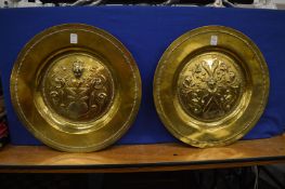 A pair of polished brass armorial dishes.