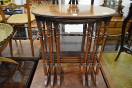 A walnut nest of three oval shaped tables.