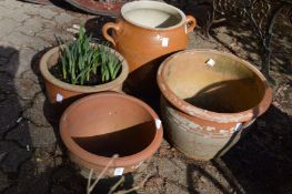 Three terracotta plant pots and a twin handled jar.