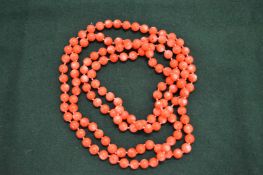 A coral coloured bead necklace.