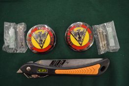 A folding saw and two car badges.