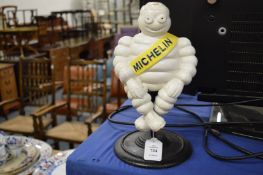 Cast iron model of a Michelin man seated on a stand.
