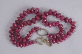A LONG RUBY NECKLACE set with seventy-four facet cut stones. 36ins long.