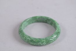 A CARVED GREEN JADE BANGLE. 3ins diameter.