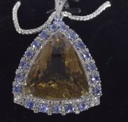 A LARGE SILVER PENDANT SET WITH A TRIANGLE CUT CITRINE, TANZANITE AND DIAMONDS on a silver chain,