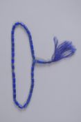 A LAPIS BEAD NECKLACE with tassel. 17ins long.